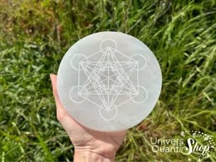 plaque de sélénite vertus, avec métatron posée dans une main dans la nature