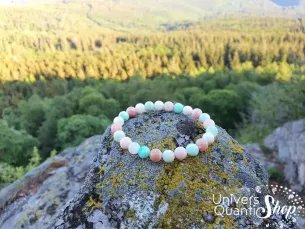bracelet opale rose et chrysoprase 08mm qualité A+ posé sur un rocher avec paysage forêt en fond