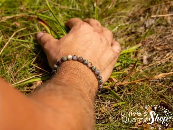 pierre des chamanes, pietersite bracelet 8mm porté sur un poignet d'homme avec main dans l'herbe