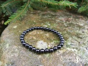 tourmaline noire pierre de protection bracelet 6mm sur un rocher avec sapin en fond