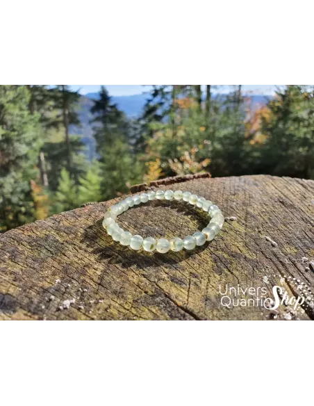 préhnite bracelet pierre naturelle verte 6mm sur un rondin de bois avec sapin en paysage préhnite bracelet pierre naturelle verte 6mm sur un rondin de bois avec sapin en paysage