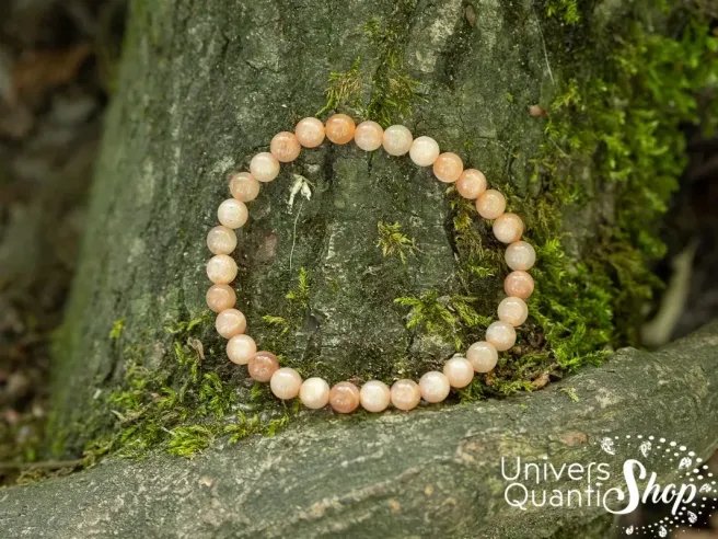 pierre de lune rose fertilité bracelet 6mm posé contre un arbre dans la forêt