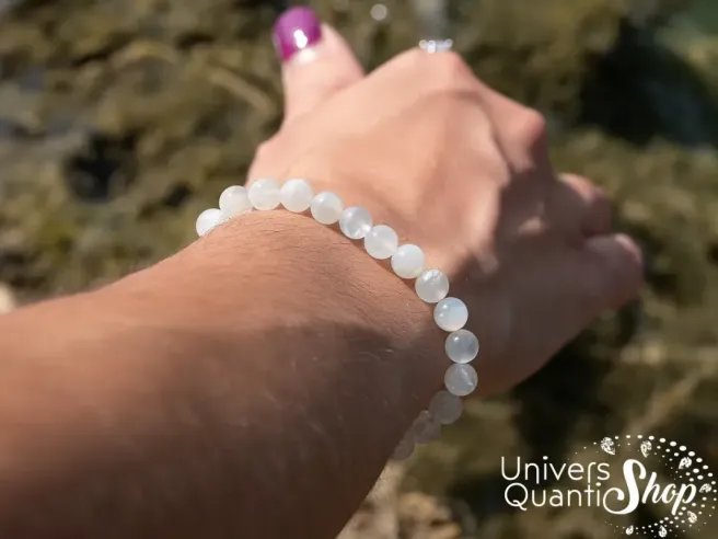 pierre de lune beige vertus bracelet lithothérapie 6mm sur un poignet de femme avec la main qui touche l'eau