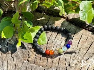 bracelet 7 chakras signification pierre de lave 8mm posé sur une souche d'arbre