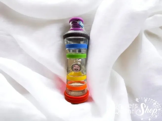eau vivante et informée, bouteille d'eau aux couleurs des 7 chakras posé sur du tissu blanc, vitalité eau