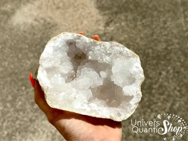 vertus géode quartz, pierre de rechargement une moitié portée dans une main