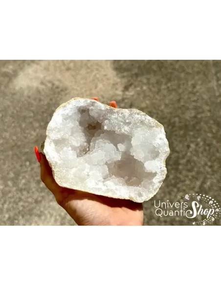vertus géode quartz, pierre de rechargement une moitié portée dans une main