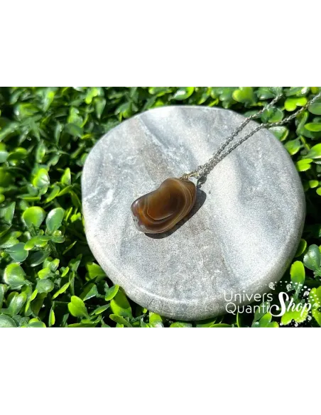 agate botswana vertus pendentif lithothérapie posé sur un bloc en marbre sur l'herbe agate botswana vertus pendentif lithothérapie posé sur un bloc en marbre sur l'herbe
