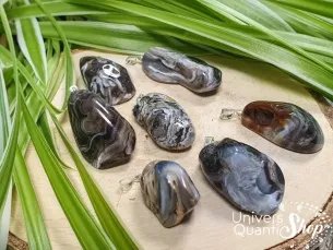 pendentif agate plume noire sur un rondin de bois, bienfaits et vertus en lithothérapie