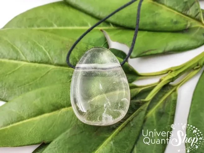 pendentif pierre cristal de roche posé sur des feuilles, vertus en lithothérapie