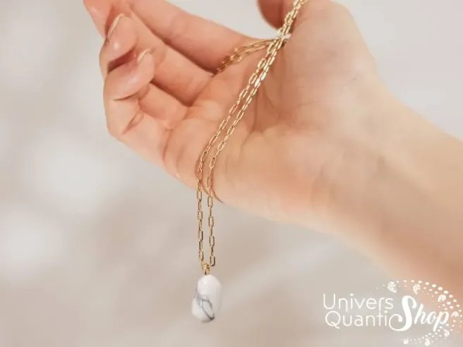 bienfaits pendentif howlite en lithothérapie, pendentif pierre naturelle porté dans une main