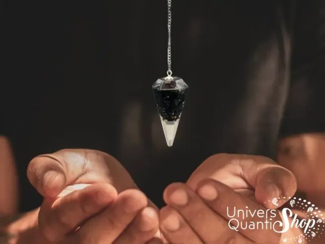 Pendule divinatoire orgonite en tourmaline noire en pointe suspendu au dessus des mains