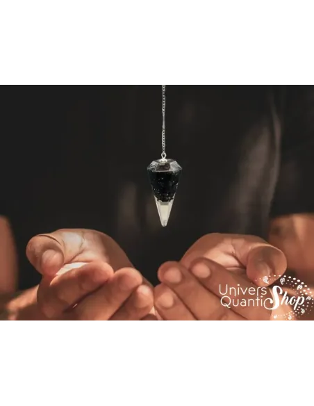 Pendule divinatoire orgonite en tourmaline noire en pointe suspendu au dessus des mains