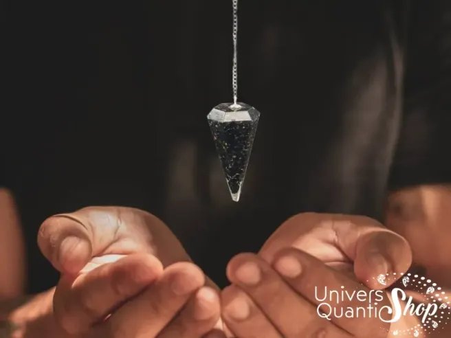 Pendule divinatoire orgonite shungite en pointe suspendu au dessus des mains - protection