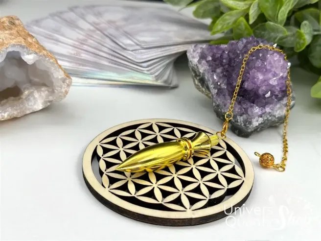 pendule divinatoire égyptien, pendule métal plaqué or posé sur une fleur de vie