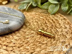 pendule isis laiton plaqué or mini posé sur un support rond en paille