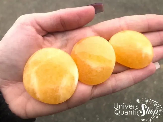 pierres plates en pierre calcite orange, pierre de positivité posées dans une main