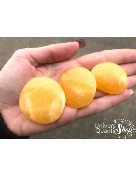 pierres plates en pierre calcite orange, pierre de positivité posées dans une main
