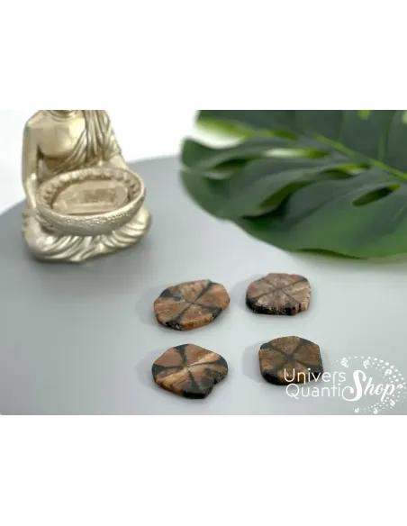 chiastolite protection pierres plates posées sur un fond gris, avec une petite statue de bouddha tenant un cristal de quartz