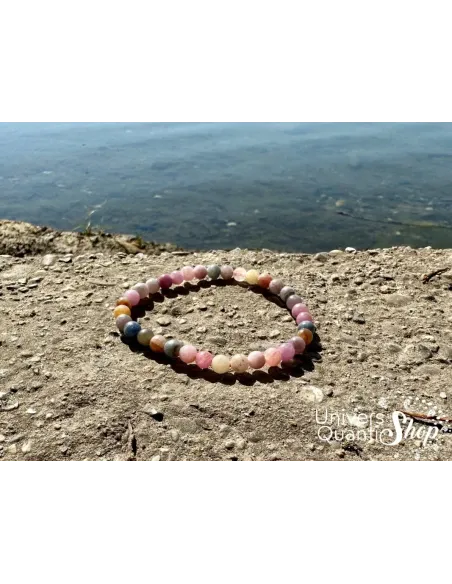 bracelet saphir multicolore clair posé sur un rebord en pierre au bord d'un lac