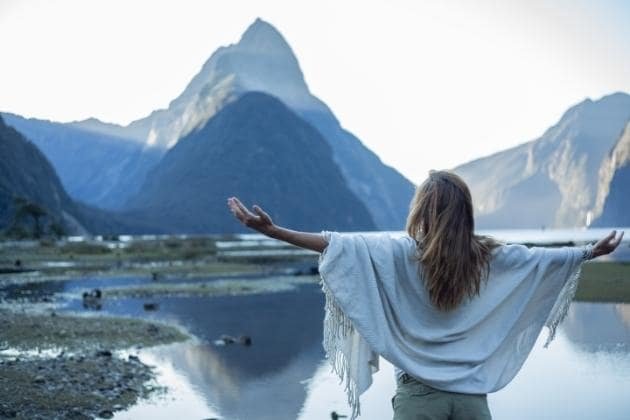 femme ouvrant les bras devant l'eau et la montagne, taux vibratoire
