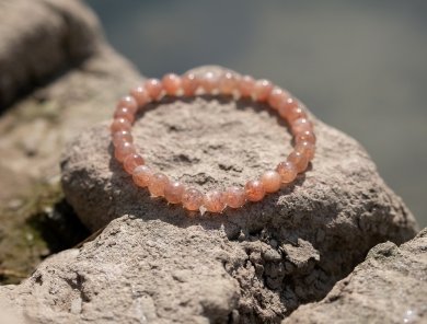 pierre du soleil bracelet posé sur un rocher au bord de l'eau